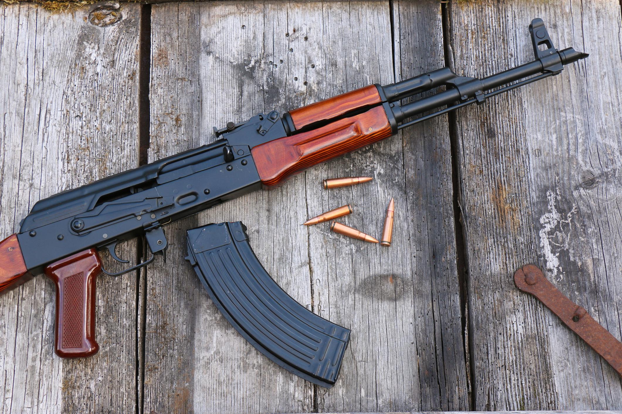 The famous Kalashnikov assault rifle with magazine and cartridges on an old, damaged board