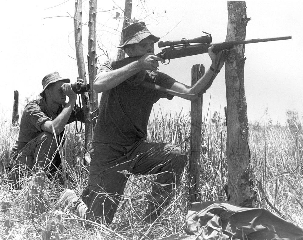 Marine sniper, PFC D. M. Taylor, sights-in on an enemy NVA rifleman harassing Marines during an operation south of Phu Bai." His rifle is a commercial Remington 700 with a 3x9 power scope