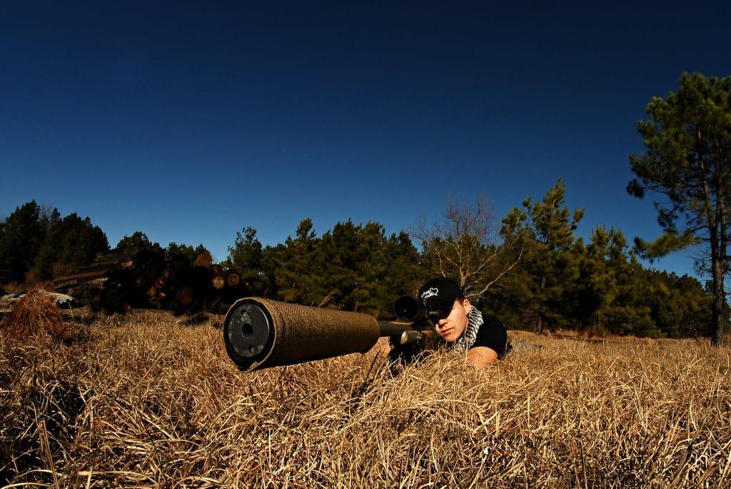 A suppressor cover being used while shooting in dry grass.