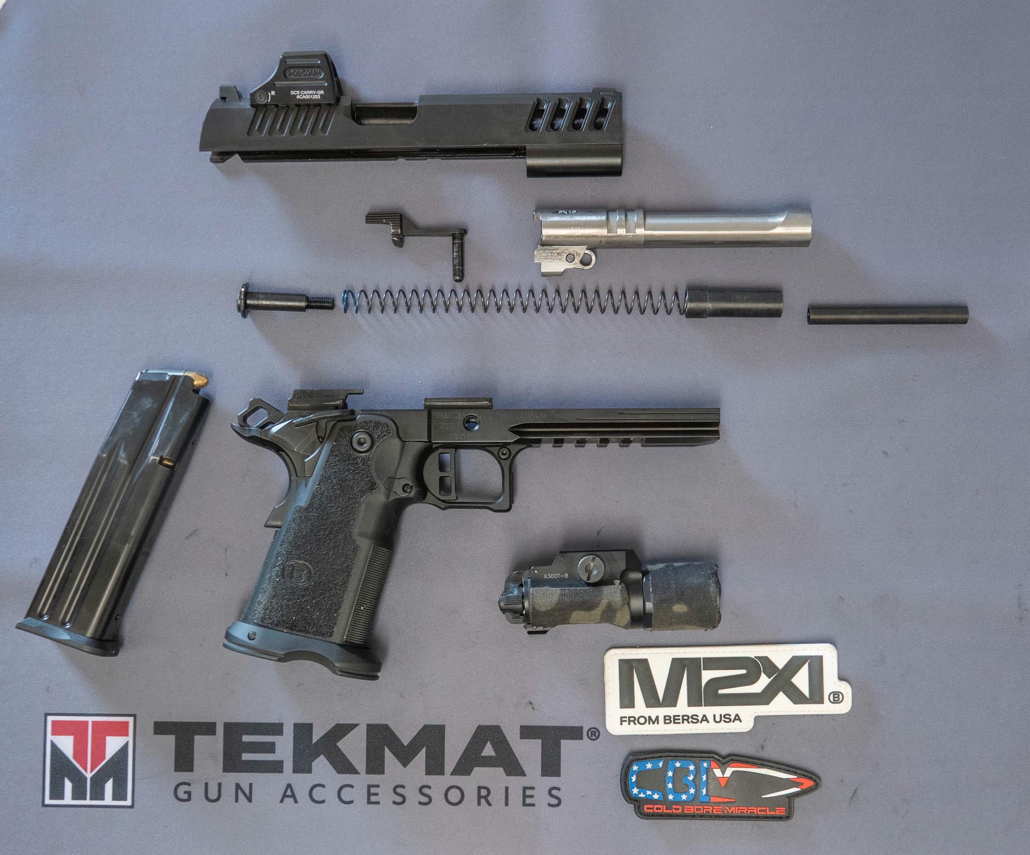 The Bersa M2Xi field-stripped on a TekMat, showing the slide, two-piece guide rod, barrel, frame, magazine, and weapon light.